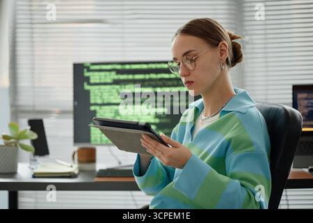 Young Woman Using Digital Tablet While Working in Modern Office Stock Photo