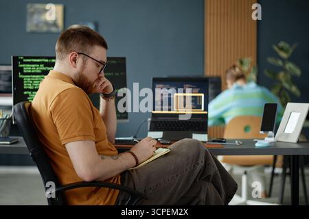 Young Adult Man Working on Software Development in Modern Office Stock Photo