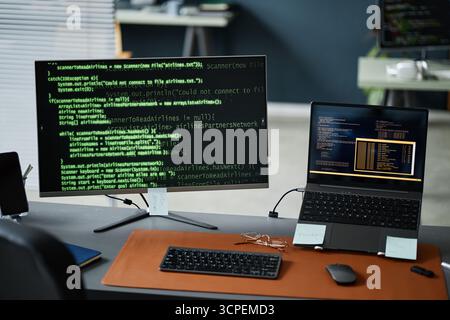 Close up of Computer Monitor and Laptop Displaying Programming Code in Office Stock Photo