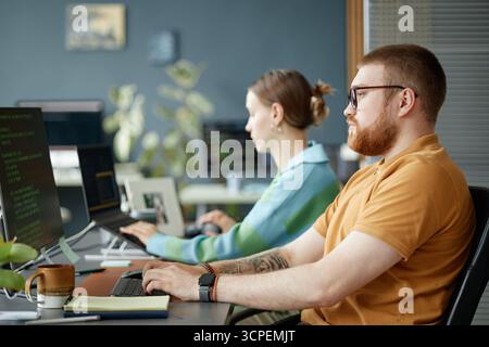 Young Man and Woman Working on Computers in Modern Office Setting Stock Photo