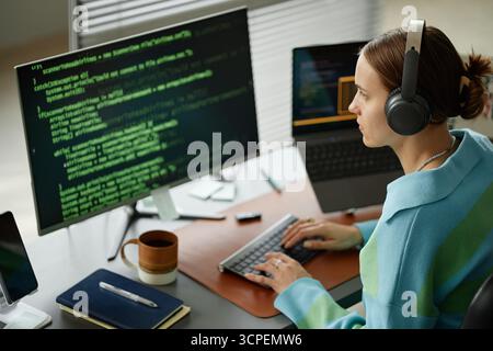 Young Woman Writing Computer Code on Desktop Computer at Workplace Stock Photo