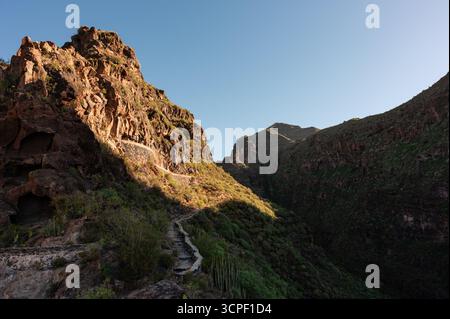 Wide shot of the Barranco del Infierno mountain path, with the morning sun illuminating one side of the mountains Stock Photo