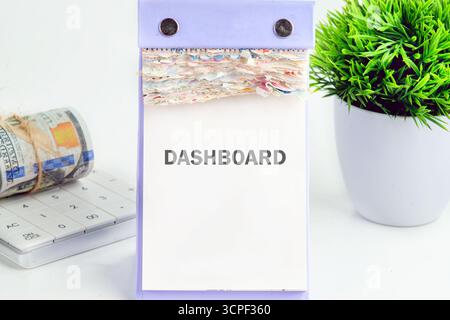 DASHBOARD word written on a desktop calendar on a white background. Analyst working with Financial Report and Business Analytics concept. Stock Photo