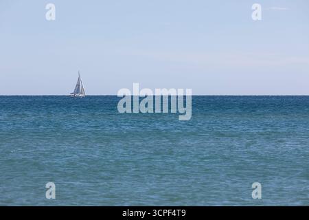 A small sailing yacht alone on a calm blue Mediterranean Sea Stock Photo