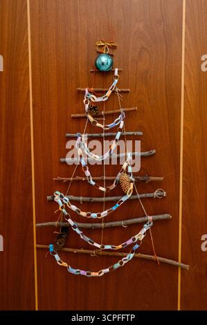 A DIY Christmas tree made from branches, paper garlands, and pine cones. Christmas decor made from natural materials: a creative tree made from branch Stock Photo