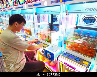 Man Playing Fishing Arcade Machine with Live Fish in Shopping Mall Stock Photo