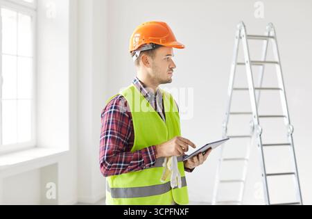 Contractor Planning Renovation Using Tablet Pc And Estimating Costs Stock Photo