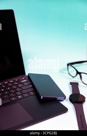 Workflow and business desk. Daily work, office and communicational supplies. A minimalistic closeup photo from a laptop, mobile phone and a smart watc Stock Photo