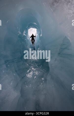 A hiker passes through a tunnel of ice on the Nigardsbreen Glacier, near Jostedal, Norway. Stock Photo