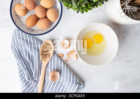 Overhead view of cracked eggs, shells, and brown eggs in bowl Stock Photo