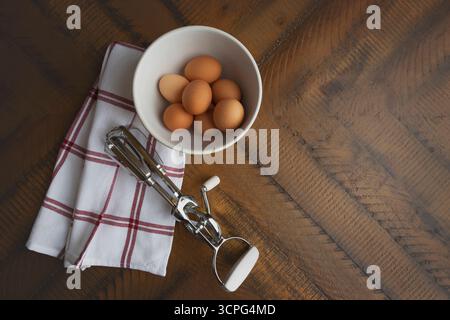 Overhead view of brown eggs in white bowl on rustic wood table Stock Photo