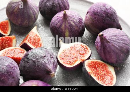 Whole and cut figs on gray plate, closeup Stock Photo