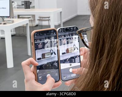 Poznan, Poland - September 20, 2025: Close-up of hands holding two smartphones with active camera applications, capturing images of audio devices for Stock Photo