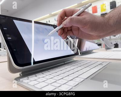 Poznan, Poland - September 20, 2025: A person's hand operates an iPad Pro using an Apple Pencil to create digital art, displayed in a brightly lit ele Stock Photo