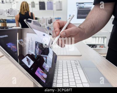 Poznan, Poland - September 20, 2025: Close-up of a hand using a digital stylus on a contemporary tablet displaying Procreate software for digital art Stock Photo