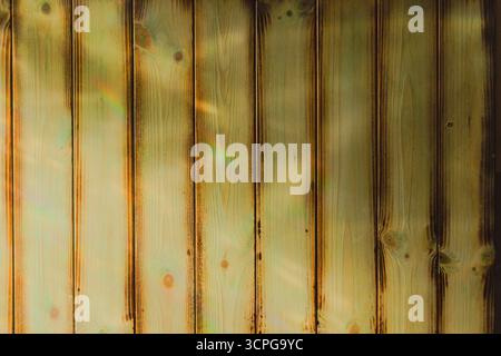 Bright sunlight playing across panelled wood which was bleached, treated with copper sulphate, with flame darkened edge. Light, rainbow, shadow, shade Stock Photo