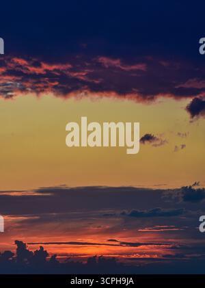 Vivid and dramatic sunset colors stretch across a cloud-filled sky, blending serenity, warmth, and the beauty of twilight. Stock Photo
