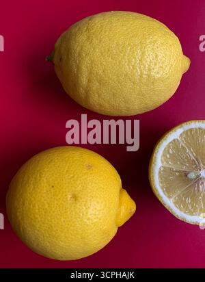Fresh lemon pattern on a vivid pink background. Flat lay. Lemons. Vitamin C. Creative minimal art. Minimal summer concept. Whole and halved lemon. Stock Photo