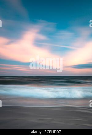 Long Exposure abstract seascape at beach at sunset with flowing ocean sea water movement and colorful sky Stock Photo