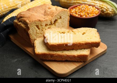 Freshly baked cornbread, cobs and seeds on black table, closeup Stock Photo