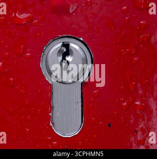 Key Lock with Red Background and Waterdrops - Signs of Security and Danger Stock Photo