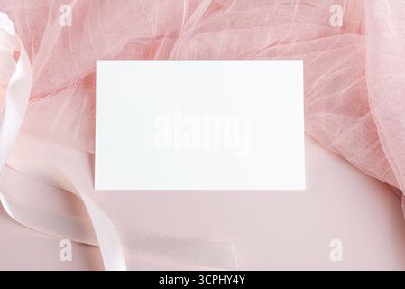 Horizontal empty card mockup template on light pastel pink fabric on pink background, design element for wedding rsvp, thank you card, greeting or inv Stock Photo