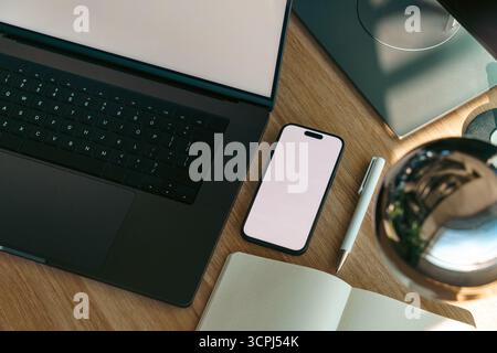 Mockup office devices laptop smartphone workspace top view. Flat lay of modern digital workspace with blank screen smartphone, black laptop keyboard, Stock Photo