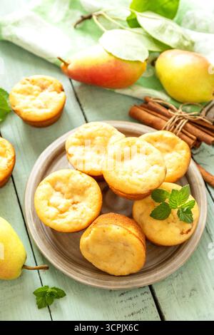 Freshly baked pear muffins with cinnamon and mint on rustic wooden table Stock Photo
