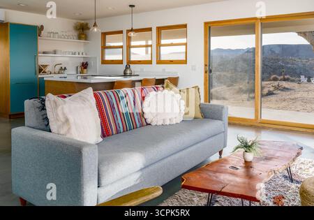 Modern desert home living room and kitchen with open floor plan sofa blanket and pillows in yucca valley california Stock Photo