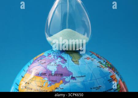 Hourglass on planet Earth, every action counts to take care of it (text in Spanish) Stock Photo