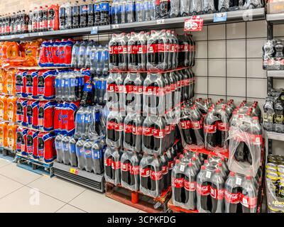 Italy - September 18, 2025: Coca-Cola, Pepsi Cola, and other brands in large plastic bottles stacked on pallets for sale in Italian discount stores. Stock Photo