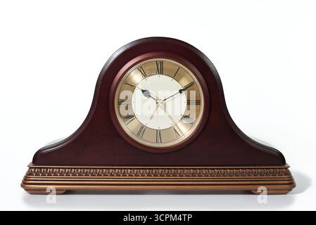 A classic, traditional mantelpiece clock made of dark wood with a bronze-colored base. A concept for time, deadlines, history, and timeless elegance. Stock Photo