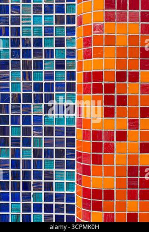 Square ceramic wall tiles in vibrant patterns. The left side features predominantly blue and teal tiles with a glossy finish, arranged in a grid. Stock Photo