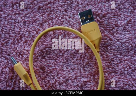 Yellow realme usb type-c cable on red background. Realme usb charging cable phone. Stock Photo