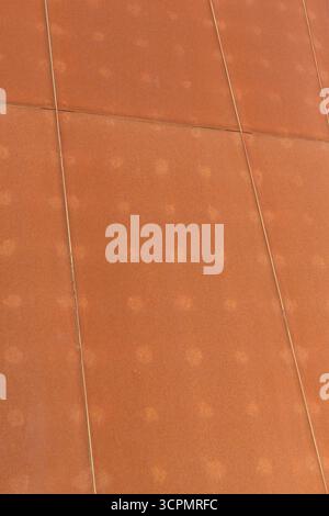 Rust-colored steel plate wall with a weathered texture, arranged in a large panel pattern. Stock Photo