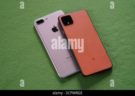 Orange google pixel 4 and pink apple iphone 7 on green background Stock Photo
