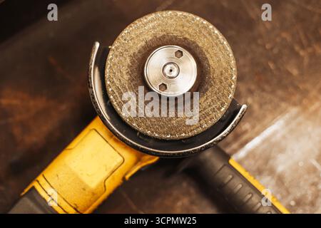 Angle grinder power tool on wooden workbench. Metal cutting and grinding equipment for workshop. Industrial construction instrument for repair. Stock Photo