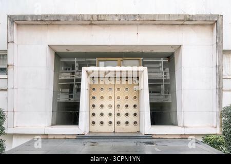 Modernist entrance featuring a pair of doors with multiple circular shapes, framed by minimalist concrete detailing. Captures the geometric symmetry Stock Photo