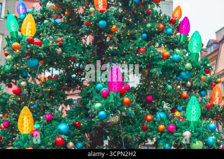Outdoor Christmas tree shines with colorful ornaments and oversized, classic multi-colored C9-style lights, creating festive and bright display Stock Photo