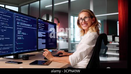 Female Programmer Coding On Multiple Computer Screens, Happy Innovative Portrait Stock Photo