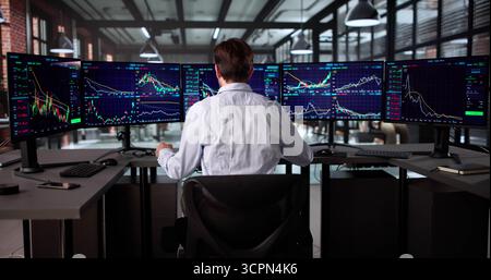 Senior Broker Analyzing Stock Market Data On Multiple Computer Screens. Stock Photo