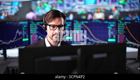 Focused Senior Stock Trader Conducting Market Research On Multiple Monitors Stock Photo