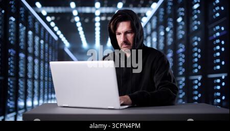 Suspicious Man In Mask Hacking Into Online Server For Malicious Purposes. Stock Photo