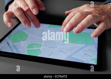 Man Navigating Through Map On Tablet In Home Office Setting. Man Running A Business From His Home Office Stock Photo