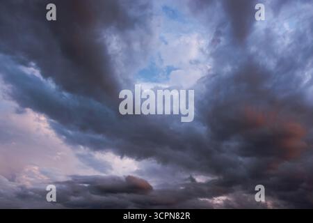 Dramatic cloudy sky with dark storm clouds and a patch of blue sky breaking through Stock Photo