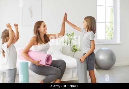 Family joyful home fitness, yogi mother and sporty kids giving high five in excitement, happy  Stock Photo