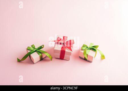 Three pastel gift boxes with colorful ribbons on pink background, flat lay composition with copy space for festive design. Top view. Stock Photo
