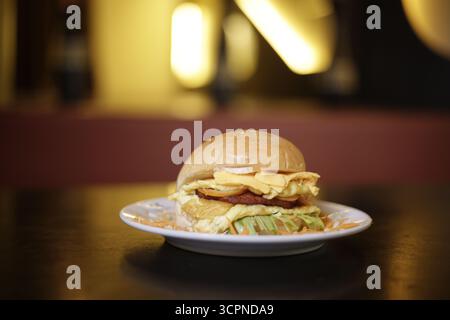 Stacked Egg and Cheese Burger with Beef Patty Served on a Plate in a Warm Setting Stock Photo