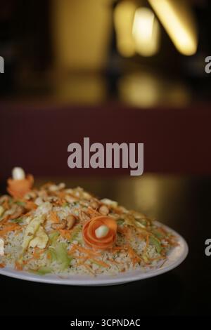 Close-up of Cashew Nut and Vegetable Fried Rice on a Platter with Warm Restaurant Background Stock Photo