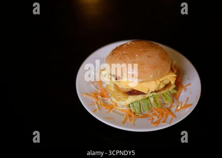 Gourmet Egg and Cheese Burger on a Sesame Seed Bun with Shredded Vegetables Stock Photo